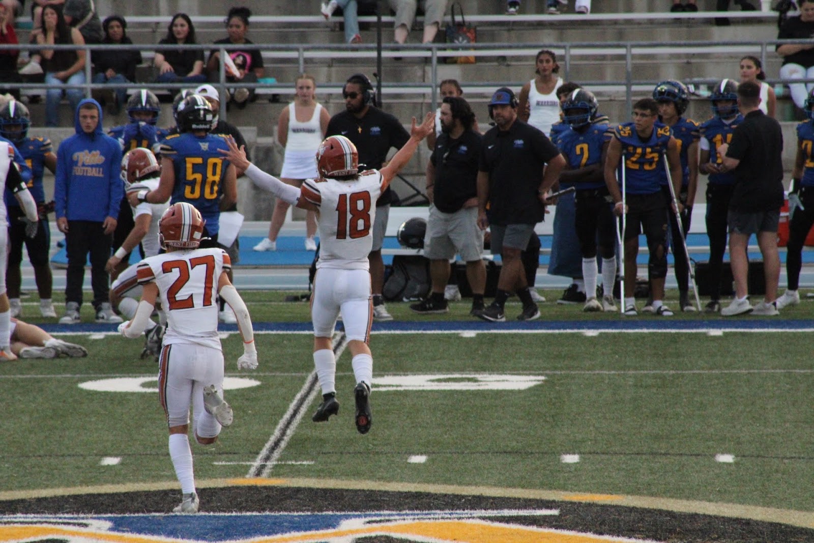Football player number 18 raising both arms in celebration after a touchdown