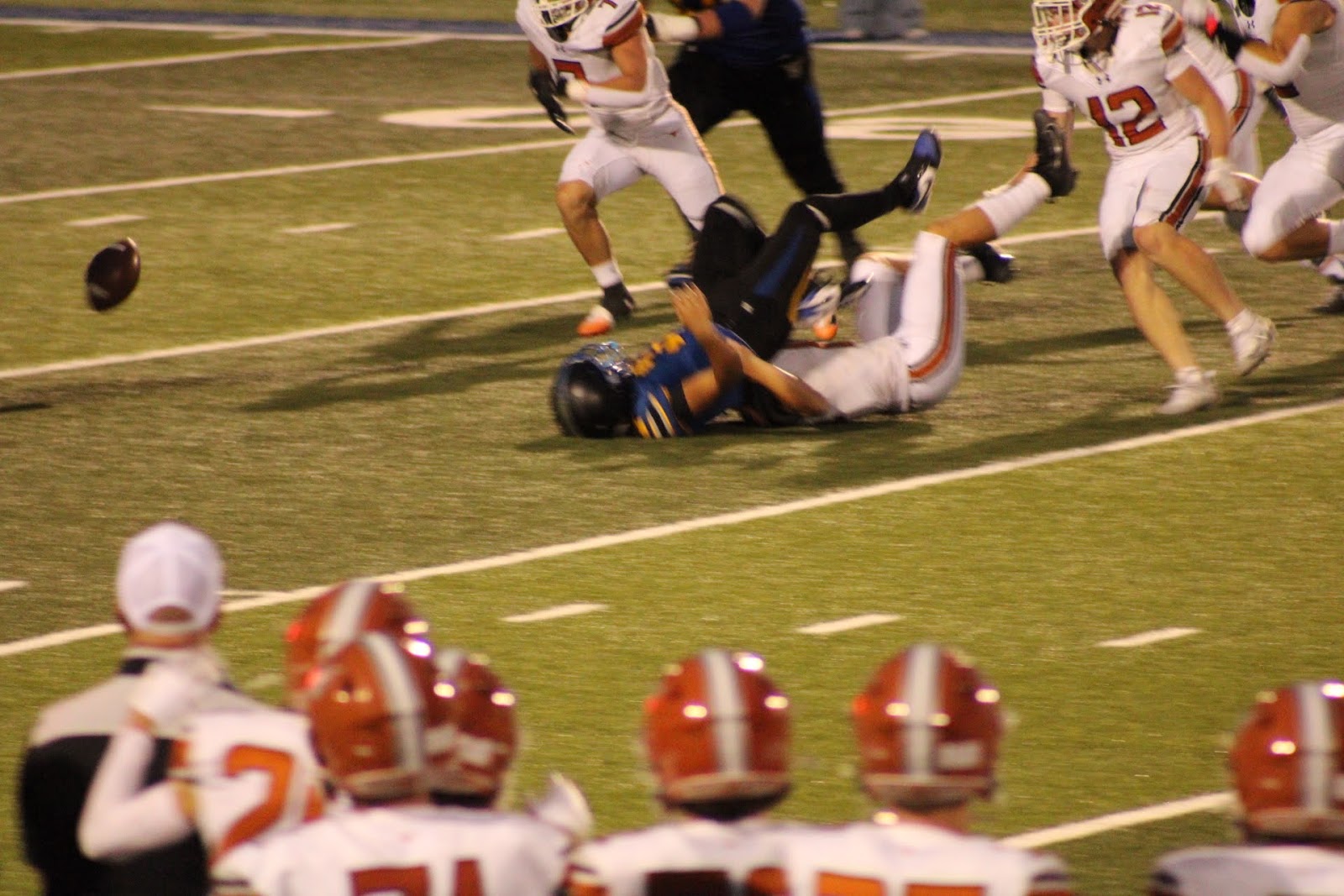 Football players diving toward a loose ball on the field