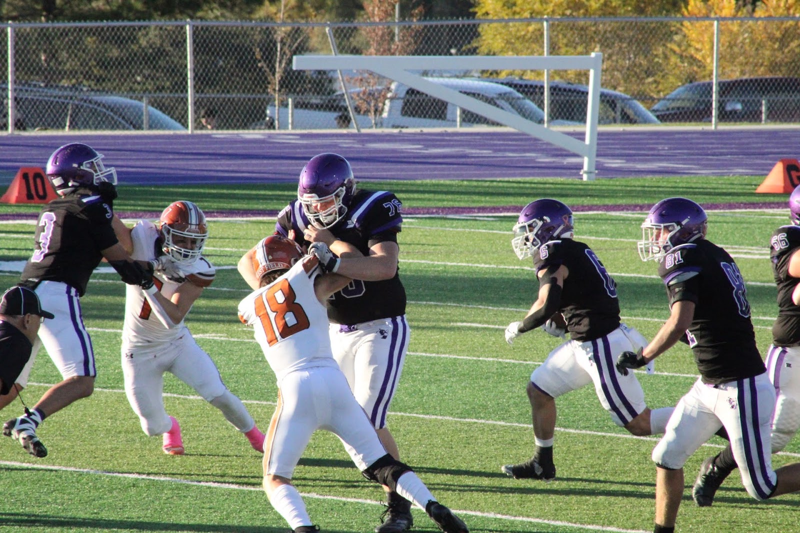 Football player breaking through a tackle attempt by defenders in purple